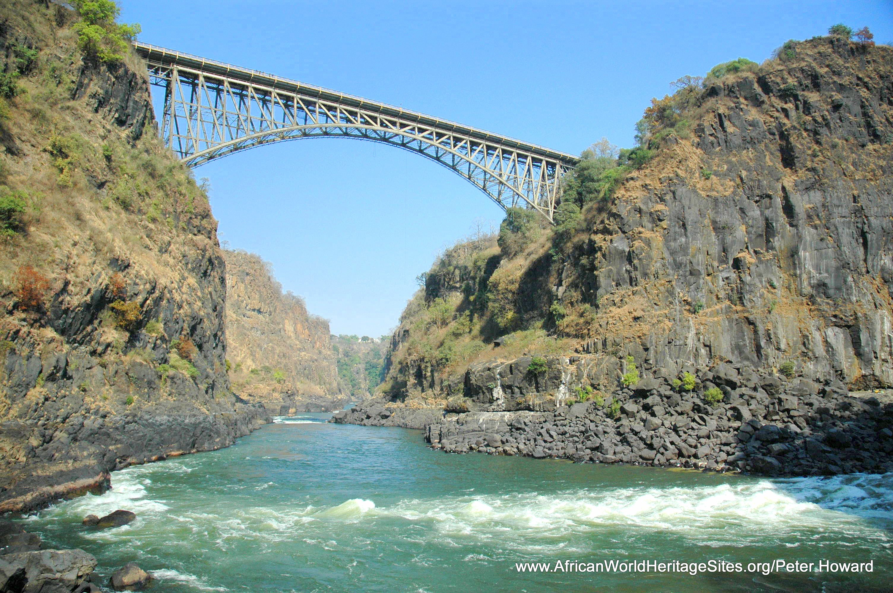 View of the iconic Victoria Falls Bridge and the Zambezi River rapids in Batoka Gorge from the base of the falls